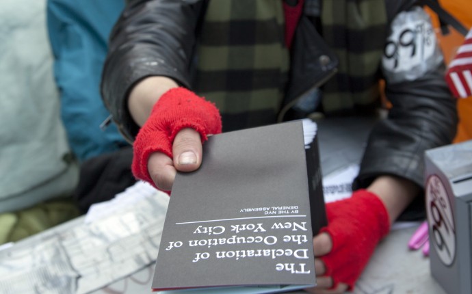 A Occupy Wall Street volunteer hands out printed copies of the Declaration of Occupy New York (Photo by Palinopsia Films)