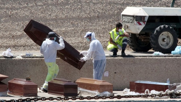 Mask-wearing rescuers put empty coffins on the Lampedusa's dock following the death of twenty-five African migrants who tried to reach Italy from Libya, Monday, Aug.1, 2011. The migrants died in the hold of a rickety boat so packed with people that the migrants could not get out as they struggled to breathe, officials said Monday after the bodies were found below deck. The 50-foot (15-meter) boat was carrying 296 people, including women and children. Hundreds of migrants fleeing unrest and conflict in Libya and across North Africa are believed to have died since the beginning of the year in desperate journeys across the Mediterranean. (AP Photo/Alessia Capasso)