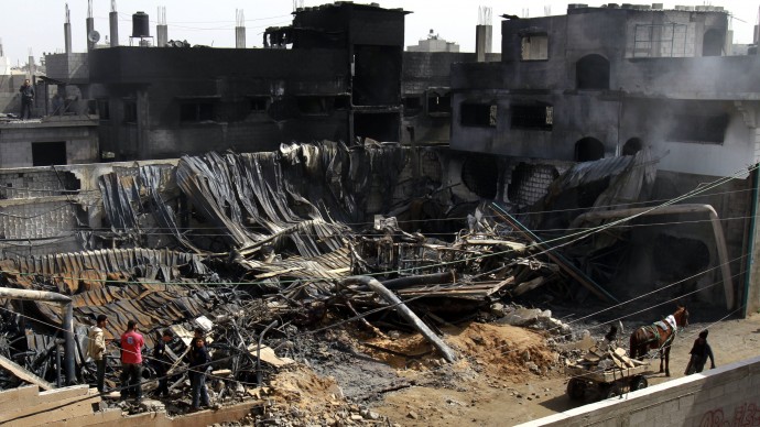 Palestinians inspect a warehouse which caught fire after an Israeli air strike near by in Gaza City, Wednesday, March 14, 2012. On Tuesday, Israel and Gaza militants agreed to a truce after four days of cross-border fighting, though there have been sporadic violations. (AP Photo/Adel Hana)