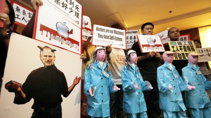 A cardboard cutout of Apple Inc. CEO Steve Jobs portrayed with devil's horns and paper figures symbolizing Chinese workers are placed by protesters outside a Foxconn's annual general meeting during a protest in Hong Kong Tuesday, June 8, 2010. Protesters picketed Foxconn's annual general meeting in Hong Kong on Tuesday, accusing both the Apple Inc. supplier and computer giant of poor corporate ethics after a recent spate of suicides at Foxconn factories in mainland China. (AP Photo/Vincent Yu)