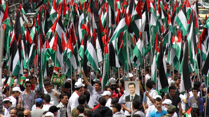 Pro-Syrian government demonstrators hold Baath party flags and a picture of President Bashar Assad at a rally at Sabe Bahrat Square to commemorate the 65th anniversary of the foundation of the Ruling Baath Arab Socialist Party in Damascus, Syria, Saturday, April 7, 2012. (AP Photo Bassem Tellawi)