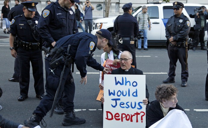 A protester sitting on Seventh Street is led away by police during an immigration reform protest outside a federal building in San Francisco, Wednesday, July 28, 2010. Hours after a federal judge temporarily halted key sections of Arizona's controversial new law, community members rallied to call upon Congress to fix the immigration system. (AP Photo/Eric Risberg)