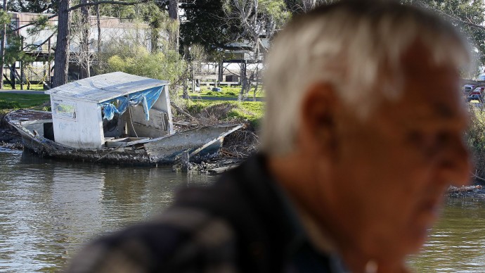In this Jan. 28, 2011 photo, an abandoned fishing boat is seen sitting on the bank of a bayou past seafood dock owner Price Billiot in the American Indian fishing village of Pointe-Aux-Chenes, La., where Billiot says he's surviving for now, thanks in part to $65,000 in emergency oil spill payments he received from BP PLC in June for his business losses. (AP Photo/Patrick Semansky)