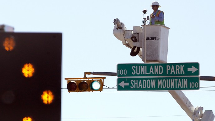 In this March 22, 2012 photo, a worker installs traffic cameras at an intersection in El Paso, Texas, above a sign directing vehicles to the border town of Sunland Park, N.M. (AP Photo/Ross D. Franklin)