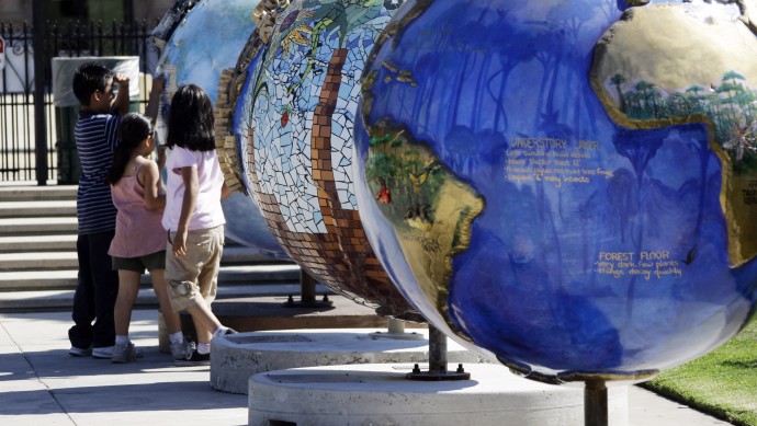 Visitors to the Rose Garden at Exposition Park view one of 50 globes, part of a public art project, "Cool Globes: Hot Ideas for a Cooler Planet," on display as part of Earth Day activities, near downtown Los Angeles Tuesday, April 21, 2009. (AP Photo/Reed Saxon)