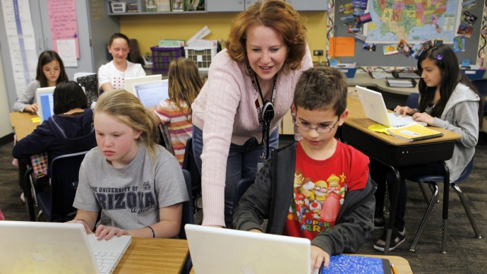 In this April 22, 2011 photo, High Plains Elementary School teacher Jennifer Williford, center,  works with Colette Jackson, 11, and Skyler Matteson, 10, right, on a computer project in her fifth grade class at the school in Englewood, Colo. Colorado has long debated the standardized tests it gives schoolchildren. Now state officials are talking about a dramatic answer to standardized tests in many grades _ none of the above. Parents are now able to choose whether or not their children participate in standardized tests. (AP Photo/Ed Andrieski)