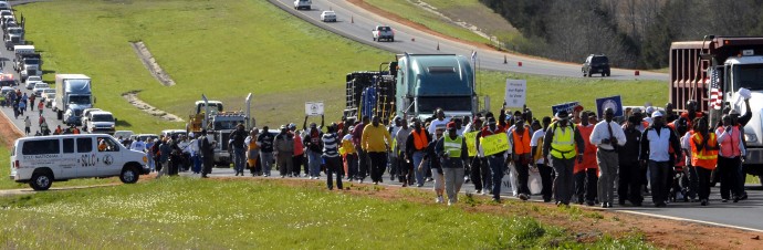 Marchers travel along Highway 80 East during the Selma Voting Rights March re-enactment Tuesday, March 6, 2012, near White Hall, Ala. Members of the Alabama Legislative Black Caucus plan to join demonstrators protesting the state's voter ID and immigration laws during a 10-mile leg of the march between Selma and Montgomery. (AP Photo/Julie Bennett)