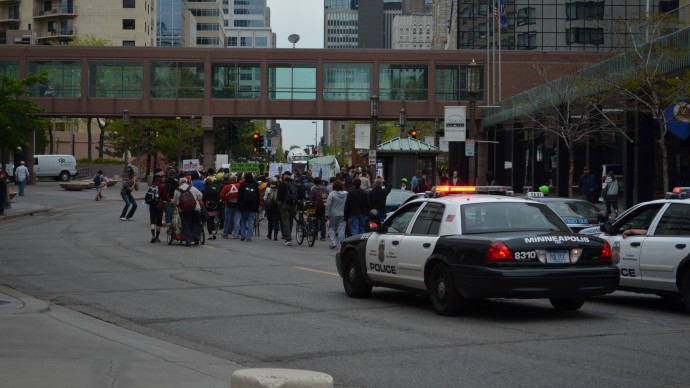 A police car follows Occupy protesters on May Day in Minneapolis. Police in Minneapolis are coming under pressure after officers allegedly offered illicit drugs to protesters as part of a police training program. (Photo MintPress/Joey LeMay)