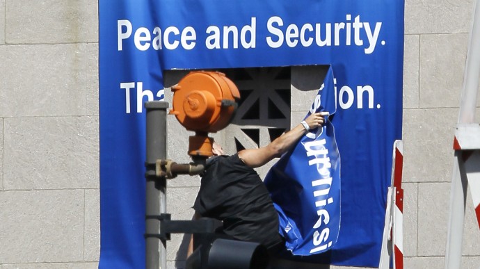 An unidentified protester rips down the NATO sign on the Chicago River bridge at Michigan Ave., during a demonstration Friday, May 18 2012, ahead of  this weekends' NATO summit in Chicago. (AP Photo/Charles Rex Arbogast)