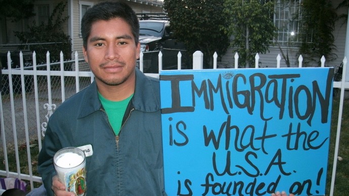 A man stands holding a sign promoting immigration. Young immigrants who are considered illegal aliens in the U.S. are pushing for President Barack Obama to move forward with pro-immigration reform. (Photo by mpeake from Flikr)