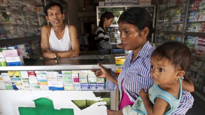 In this Aug. 26, 2009 file photo, a merchant speaks with a woman holding her sick child at a pharmacy in Pailin, Cambodia. (AP Photo/David Longstreath, File)