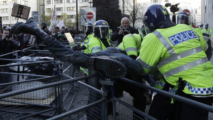 Police officers in riot gear pull a protester over barriers to detain him. Thousands of students marched to protest the big increase in university tuition fees. (AP Photo/Matt Dunham)