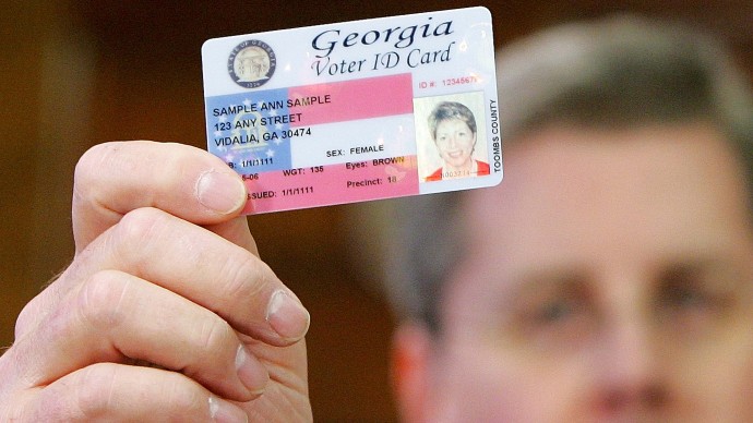 Georgia Gov. Sonny Perdue holds up a sample Voter ID after signing the bill into law at the Capitol in Atlanta, Jan. 26, 2006. Sen. Cecil Staton, R-Macon, sponsor of the Voter ID legislation in the Senate is seen in the background. (AP Photo/Ric Feld)