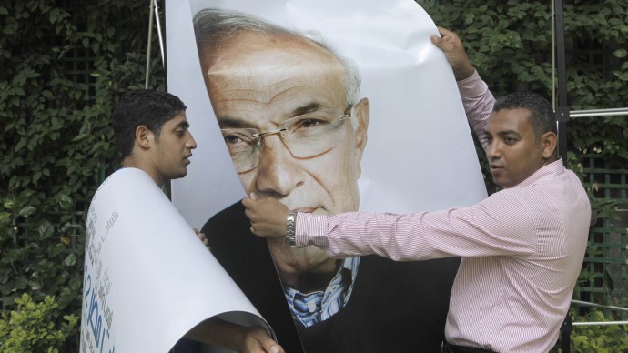 Egyptian workers uninstall a billboard showing presidential candidate Ahmed Shafiq, at his campaign headquarters office following a press conference in Cairo, Egypt, Monday, June 18, 2012. (AP Photo/Amr Nabil)