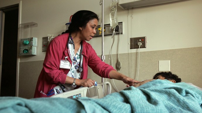 Charge nurse Eshter Marania checks on a patient at a hospital in San Francisco. Six hospitals in Southern California were recently fined for health care violations. (AP Photo/Jeff Chiu)