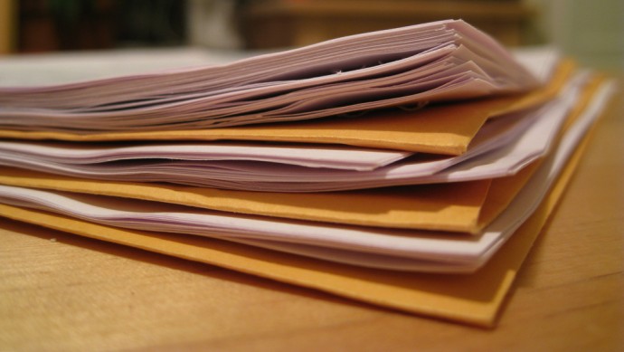 A stack of papers in files sits on a table. (Photo by moppet65535 via Flikr)