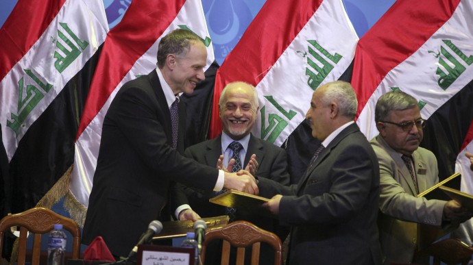 In this Jan. 25, 2010, file photo, Exxon Mobil Corp. Director Richard C. Vierbuchen left, shakes hands with Dhiya Jaafar, acting chief of Iraq's South Oil Company, second right, as then Iraqi Oil Minister Hussain al-Shahristani, center,claps during a signing ceremony in Baghdad, Iraq. An oil exploration deal signed by the U.S. oil giant ExxonMobil with Iraq's self-ruled Kurdish region is deepening divisions between Kurds and Arabs at a crucial time as U.S. troops are leaving. (AP Photo/Karim Kadim, File)