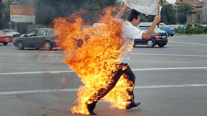 Iulian Grosu runs after setting himself on fire in Bucharest, Romania, Monday July 11 2005 outside the government headquarters. A man in Burmingham, Ala. recently set himself on fire in the what many are calling the first financially-motivated self-immolation in the United States (AP Photo/Adrian Martalogu)