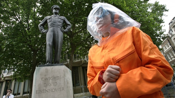 Under the statue of former U.S. President Dwight D. Eisenhower outside the U.S embassy in central London, a protester dressed as 'Guantanamo Bay prison detainee' in orange jumpsuit and a plastic bag on her head as a hood, participates in a play called 'Closing Down Torture Airlines' during a demonstration, Sunday June 25, 2006. (AP Photo/Lefteris Pitarakis)
