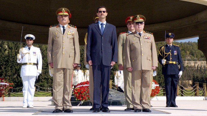 In this Thursday, Oct. 6, 2005 file photo, Syrian President Bashar Assad, center, Syrian Defense Minister Maj. Gen. Hassan Turkmani, foreground right, and Ali Habib, the Syrian Chief of Staff, foreground left, during a visit to the tomb of the unknown soldier in Damascus to mark the 32nd anniversary of the 1973 Arab-Israeli war known as the October war. (AP Photo/SANA, File)
