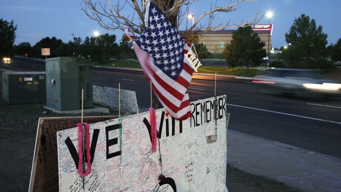 A sign that reads "We Will Remember," hangs under a U.S. flag across the street from the Century 16 movie theater, early Friday, July 27, 2012 in Aurora, Colo. (AP Photo/Ted S. Warren)