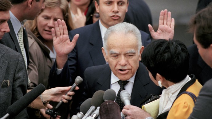 In this Nov. 22, 1991 file photo, an aide to Israeli Prime Minister Yitzhak Shamir asks reporters to back off as Shamir leaves a meeting with President Bush White House. (AP Photo/Barry Thumma, File)