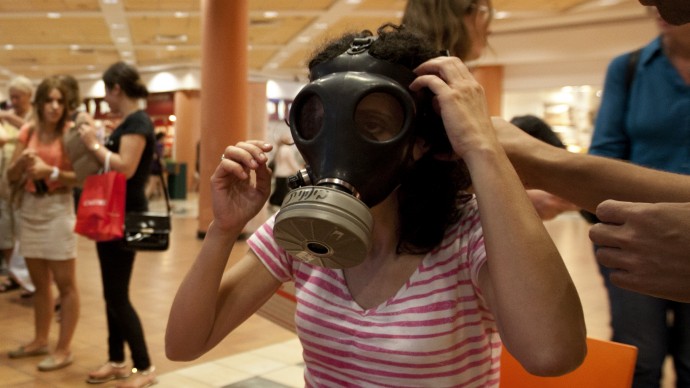 Israeli Hagit Ohana tries on a gas mask at a distribution center in a shopping mall in Mevaseret Zion near Jerusalem, Wednesday, July 25, 2012. (AP Photo/Sebastian Scheiner)