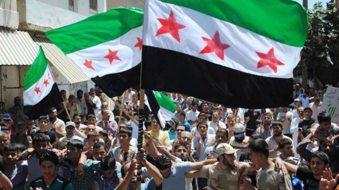 In this citizen journalism image provided by the Local Coordination Committees in Syria and accessed on Friday, June 29, 2012, protesters wave Syrian revolutionary flags and chant slogans during a demonstration in Idlib, north Syria.(AP Photo/Local Coordination Committees in Syria)