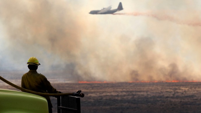 Luke Fuller, with Salmon Track Rural Fire District, watches an air tanker drop retardant on a wildfire north of Jackpot, Nev., on Tuesday, July 10, 2012. (AP Photo/The Times-News, Ashley Smith)