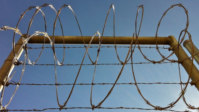 Barbed wire hangs over a security fence March 3, 2012. (Photo by JMacPherson via Flikr)