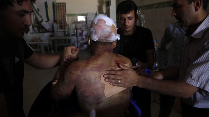 Mahmoud, a 21-year-old Palestinian resident of Syria, receives treatment in a field hospital after he was found Monday, Aug. 6, 2012, with three gunshot wounds in the town of Anadan on the outskirts of Aleppo, Syria. (AP Photo)