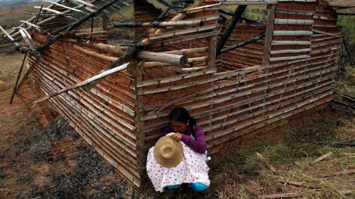 An Indian woman breast feeds her baby behind a burned-out home in Piendamo in Colombia's southern Cauca state, Saturday, Aug. 11, 2012. (AP Photo/Juan B Diaz)