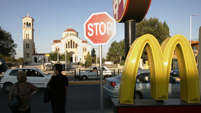 In this Aug. 19, 2004 file photo, commuters stand near a McDonald's restaurant in Marathon, Greece. (AP Photo/Lefteris Pitarakis)