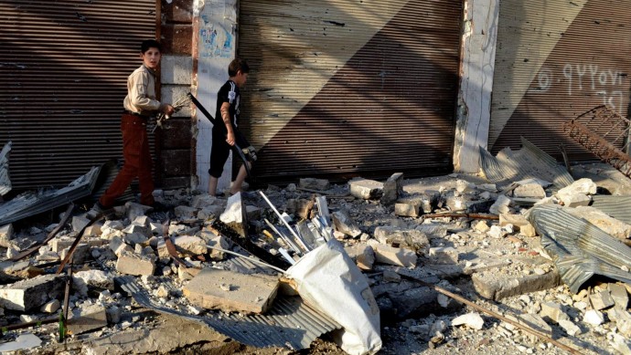 In this citizen journalism image taken on Saturday, July 28, 2012 and provided by Edlib News Network ENN, Syrian boys walk in the rubble of destroyed houses in Maarat al-Numaan on the eastern edge of Idlib province, northern Syria. (AP Photo/Edlib News Network ENN)