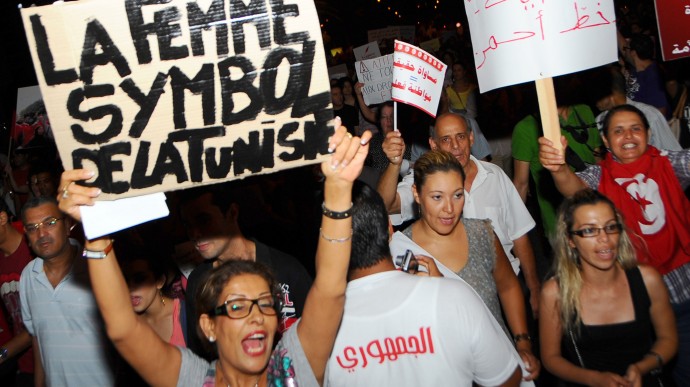 In this Monday, Aug. 13, 2012 photo Tunisian women carry placards protesting their rights which read: "women the symbol of Tunisia" left, and "fights for women rights", right, as they march in Tunis. (AP Photo/Hassene Dridi)
