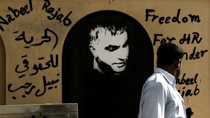 A man walks past a wall with human rights defender Nabeel Rajab, center, and Arabic, left, that reads, "freedom to human rights defender Nabeel Rajab," on it in the northern village of Barbar, Bahrain, Sunday, Aug. 12, 2012. (AP Photo/Hasan Jamali)
