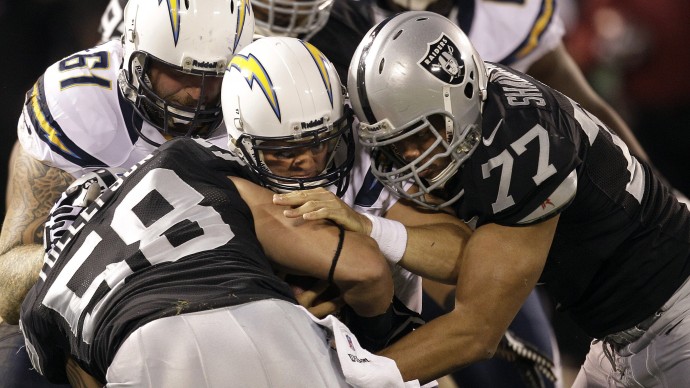 San Diego Chargers quarterback Philip Rivers is sacked by Oakland Raiders defensive end Dave Tollefson (58) and defensive end Matt Shaughnessy (77) during the first quarter of an NFL football game in Oakland, Calif., Monday, Sept. 10, 2012. (AP Photo/Ben Margot)