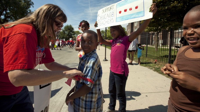 Karen Rieck, a teacher at Faraday Elementary School, greets her students as they show support for public school teachers rallying on Wednesday, Sept. 12, 2012 in West Chicago. (AP Photo/Sitthixay Ditthavong)