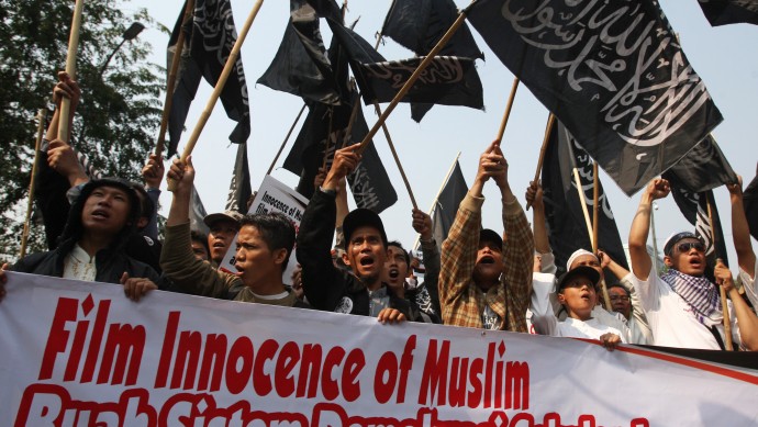 Indonesian muslims shout slogans as they hold a banner reads "Innocence of Muslims is the result of secular democracy" during a protest against the low-budget film that ridicules Islam and depicts the Prophet Muhammad as a fraud, outside the US Embassy in Jakarta, Indonesia, Friday, Sept. 14, 2012. (AP Photo/Achmad Ibrahim)