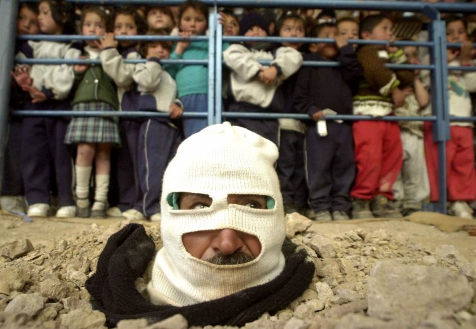 Buried up to his head, a community leader stages a protest at a Catholic Church in poor neighborhood of southern Bogota, Colombia Wednesday, June 12, 2002. (AP Photo/Javier Galeano)