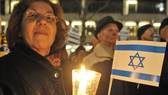 A woman holds a candle and an Israeli flag during a pro-Israel demonstration. (AP Photo/Fabian Bimmer)