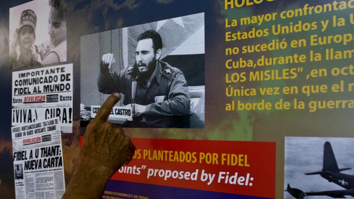An exhibit worker points at a photo of Cuba's former leader Fidel Castro that is part of an exhibit on the Cuban missile crisis in a former bunker, currently the garden of the Hotel National, in Havana, Cuba, Friday, Oct. 19, 2012. (AP Photo/Ramon Espinosa)