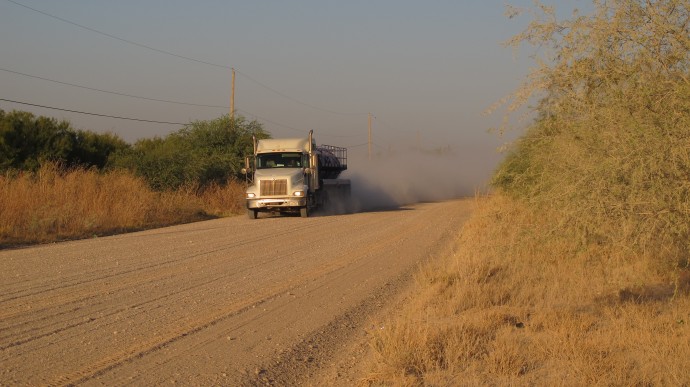 A truck travels along the stretch of gravel road near La Joya, Texas, Friday Oct. 26, 2012, where a Texas Department of Public Safety helicopter and sharpshooter assisted the previous day in the chase of a suspected illegal immigrant smuggler. Two people in the fleeing vehicle were killed and a third was wounded. (AP Photo/Chris Sherman)