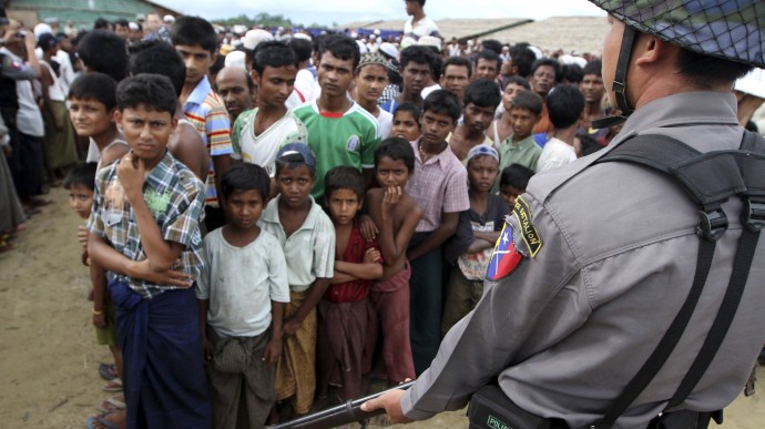 In this photo taken on Sept. 8, 2012, a policeman provides security as Muslims gather to meet U.S. Ambassador to Myanmar Derek Mitchell, unseen, at a refugee camp in Sittwe, Rakhine State, western Myanmar. (AP Photo/Khin Maung Win)
