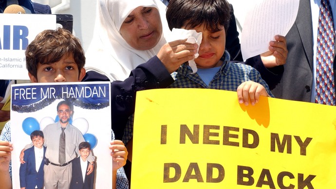 Entesar Hamdan, center, wipes tears from the face of her 10-year-old son, Albara, right, as his 8-year-old brother, Omar, holds a poster of the two boys with their father, Abdel Jabbar Hamdan, of Jordan, during a news conference and rally sponsored by the Council on American-Islamic Relations, Friday, July 30, 2004, in Santa Ana, Calif. (AP Photo/Rene Macura)
