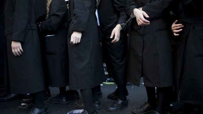Handcuffed Ultra Orthodox Jewish men and children participate in protest against attempts to draft members of the cloistered community into the Israeli military, in an ultra Orthodox neighborhood in Jerusalem, Israel, Monday, July 16, 2012. (AP Photo/Oded Balilty)