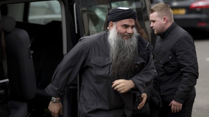 Abu Qatada, left, gets out of the rear of a vehicle as he returns to his residence in London, Tuesday, Nov. 13, 2012. (AP Photo/Matt Dunham)