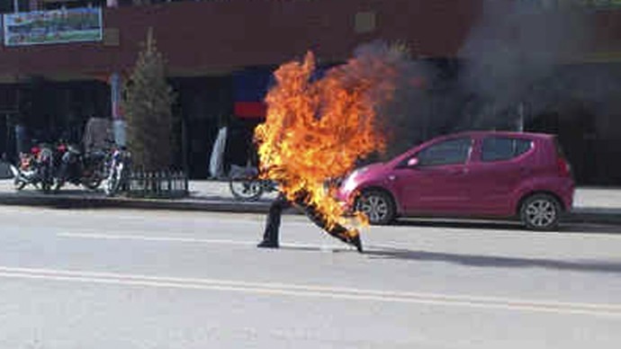 In this photo taken Tuesday, Oct 23, 2012 and released by London-based rights group Freetibet.org, Dorje Rinchen, a farmer in his late 50s, runs after setting himself on fire on the main street in Xiahe in northwestern China's Gansu province. (AP Photo/Freetibet.org)