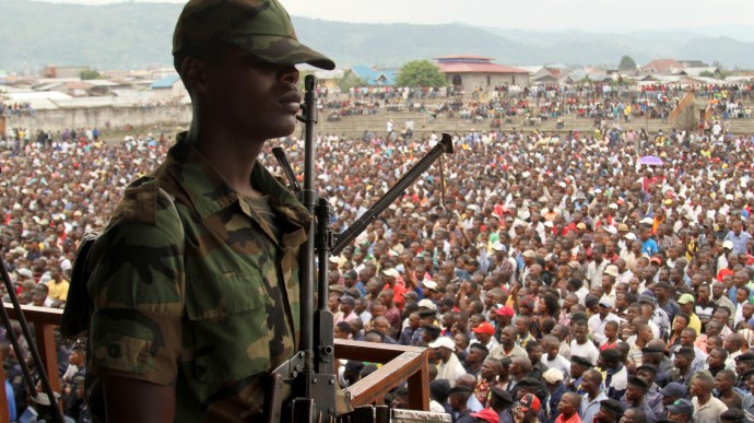 A soldier from the M23 rebel group looks on as thousands of Congolese people listen during an M23 rally, in Goma, eastern Congo, Wednesday, Nov. 21, 2012. (AP Photo/Marc Hofer)