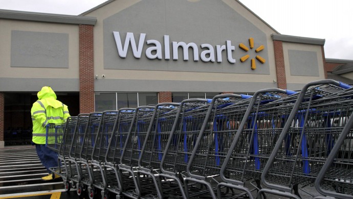 In this Tuesday, Nov. 13, 2012 photo a worker pulls a line of shopping carts toward a Walmart store in North Kingstown, R.I. (AP Photo/Steven Senne)